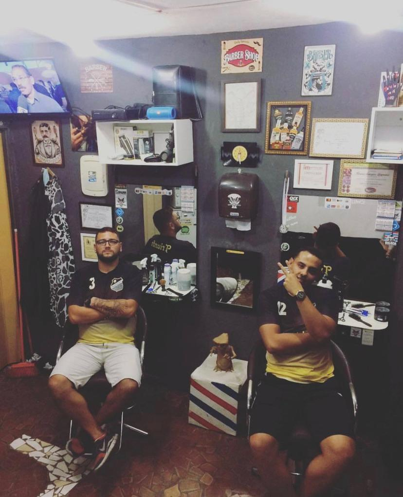 Interior do primeiro salão da barbearia com diplomas e cadeiras